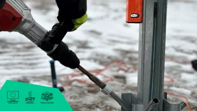Attēls: Vīrietis tur urbjmašīnu, liek konstrukciju