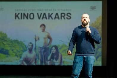 Vīrietis ar mikrofonu rokās uz skatuves